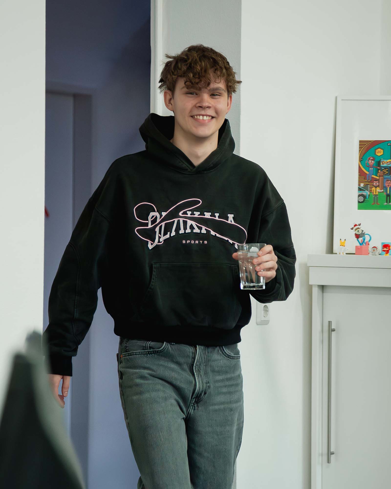 Ein dualer Student der Agentur betritt das Büro mit einem Glas Wasser